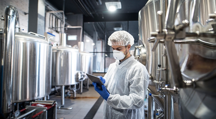 technologist-white-protective-clothes-checking-production-his-tablet