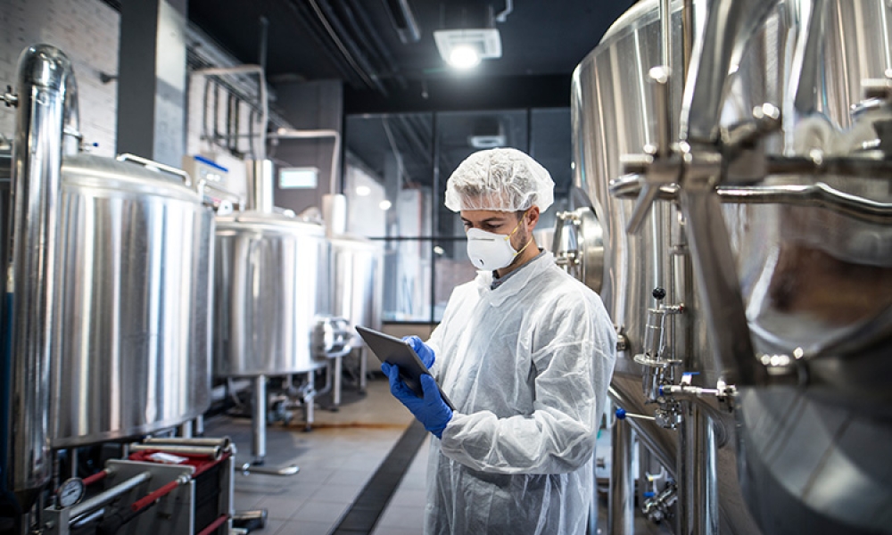 technologist-white-protective-clothes-checking-production-his-tablet